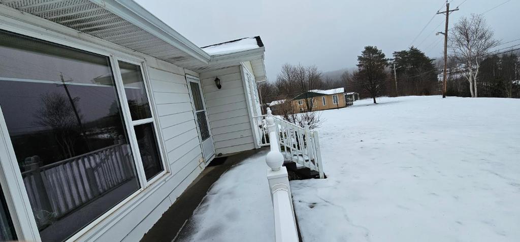a porch of a house with snow on the ground at Fair Isle Motel & The Nest in Whycocomagh