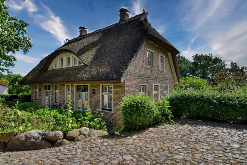 a small brick house with a thatched roof at Ferienhaus Classic im Kapitäns Hus Rügen in Putbus
