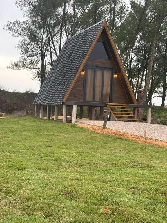 a small cabin with a metal roof in a field at Cabana Aroma do Mar in Jaguaruna