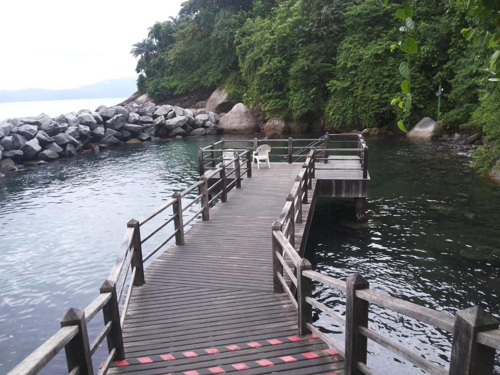 a dog standing on a wooden bridge over the water at Apartamento Porto Real Brites in Mangaratiba