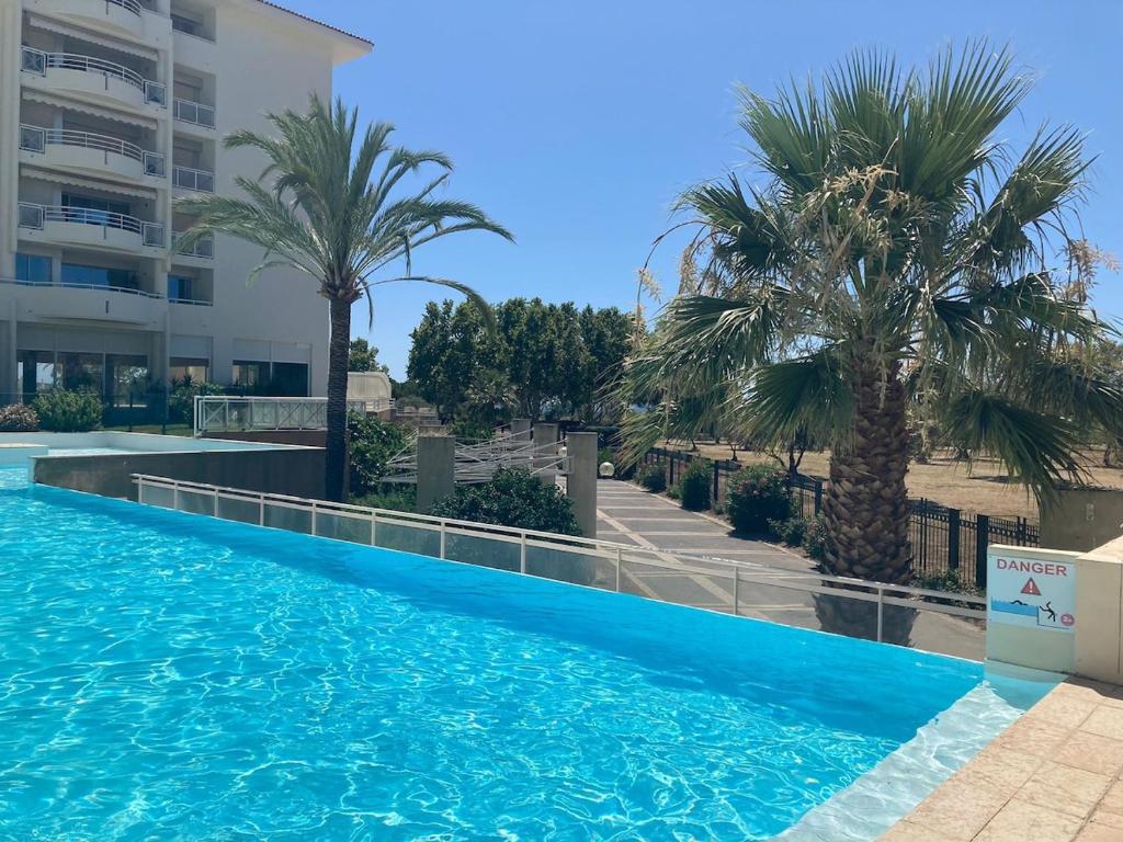 une piscine avec des palmiers et un bâtiment dans l'établissement F2 totalement rénové, 200 m de la plage, piscine, parking, tout à pieds, à Antibes