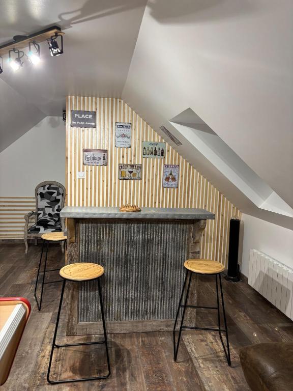 un bar avec trois tabourets dans une pièce dans l'établissement Les Rolliannes Maison au village, à Surques