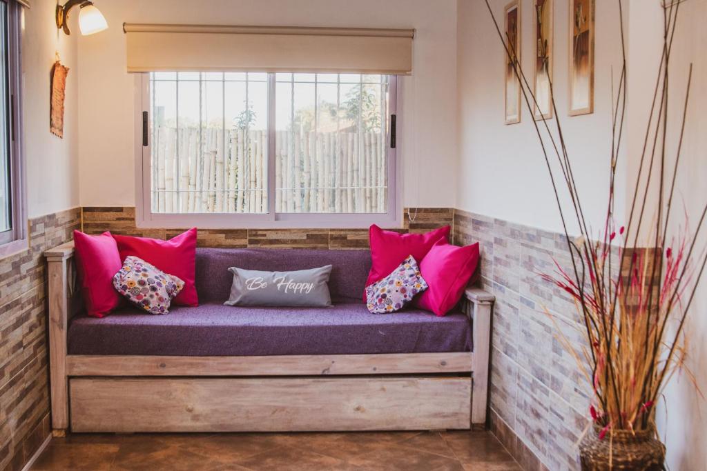 eine Bank in einem Fenster mit Kissen darauf in der Unterkunft Cabaña Morada del Cerro - Cabaña Chañar - in Capilla del Monte