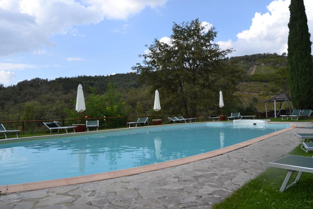 duży basen z krzesłami i parasolami w obiekcie Borgo Casa al Vento w mieście Gaiole in Chianti