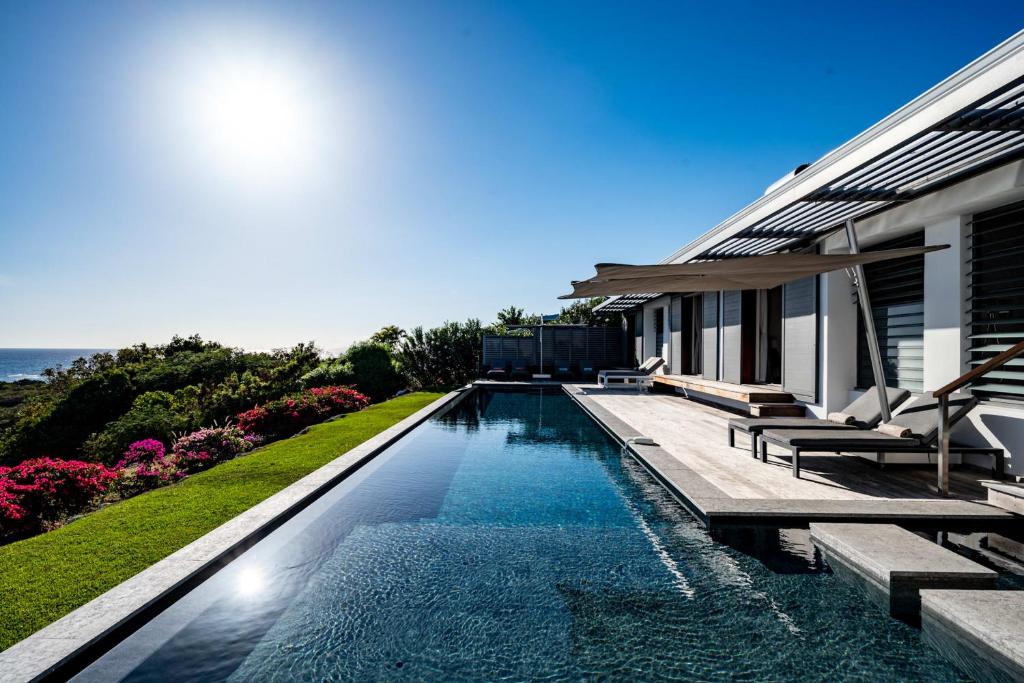 a swimming pool in front of a house at Villa Belle Galante in Grand-Bourg