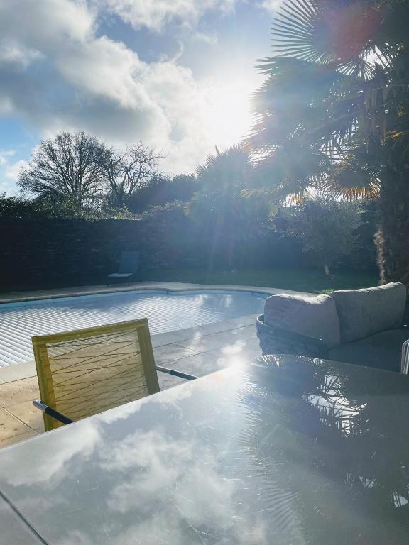 a view of a pool with a couch and a table at Comme une evidence in La Chapelle aux Pies