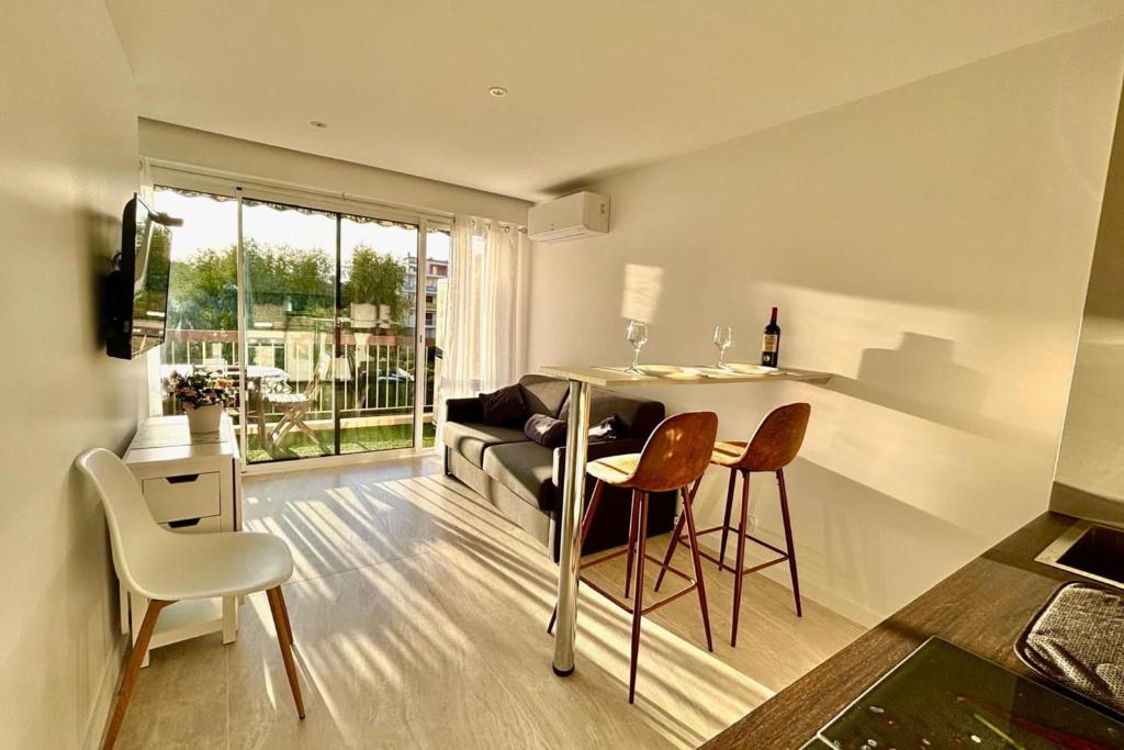 un salon avec une table, des chaises et un canapé dans l'établissement One-bedr ap 50m from the beach terrace swimming pool air con, à Antibes