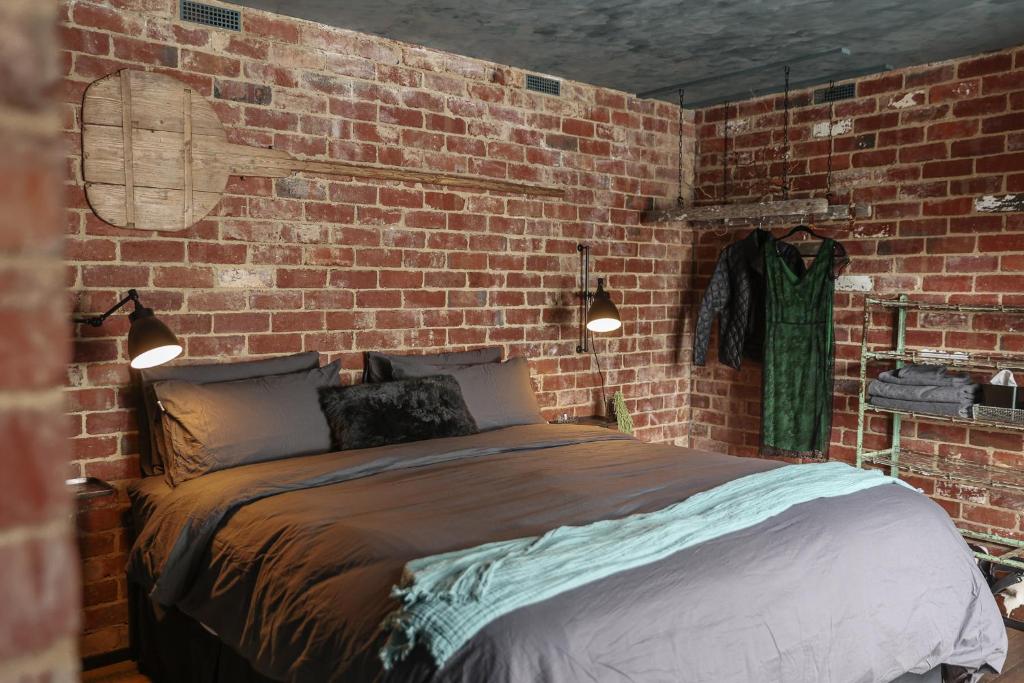 a bedroom with a brick wall with a bed at Braithwaite Hobart - Chic Retreat with Outdoor Bath in Hobart