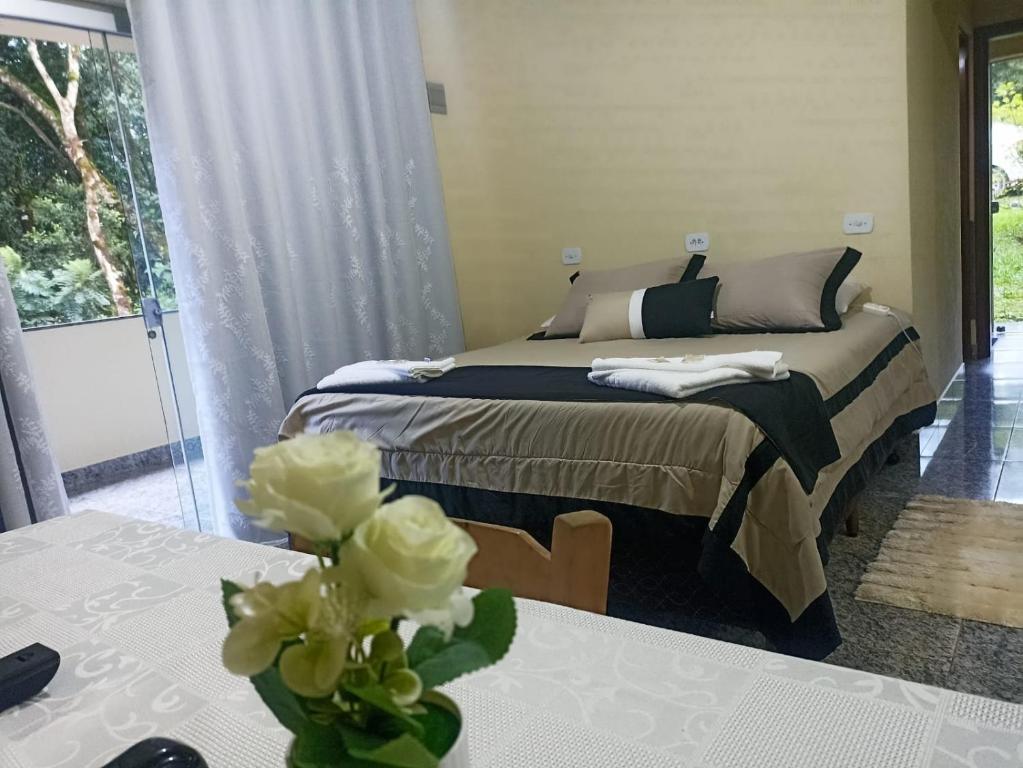 モンテ・ヴェルデにあるChalés Caminho das Pedrasのベッドと花瓶が置かれたテーブルのある寝室