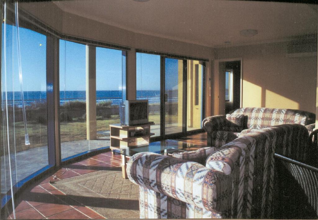 a living room with two couches and a view of the ocean at Horizons Beachfront Apartment in Port Fairy