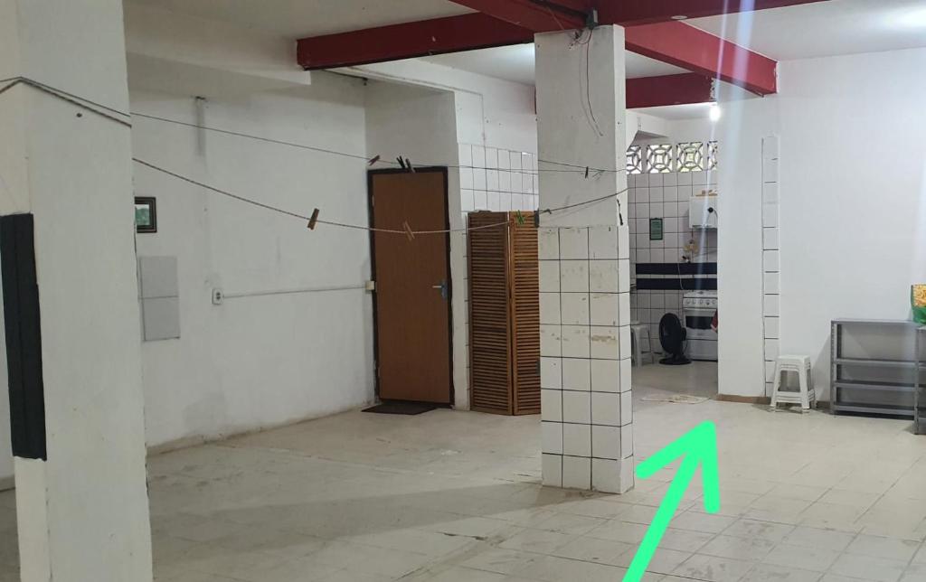 a room with a green arrow pointing to a door at Quarto com cozinha funcional in Guarapari