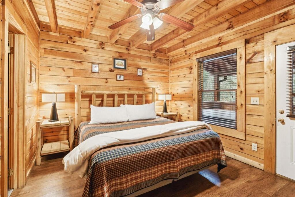 a log cabin bedroom with a bed and a ceiling fan at Cozy 5BR Cabin Near Dollywood in Pigeon Forge