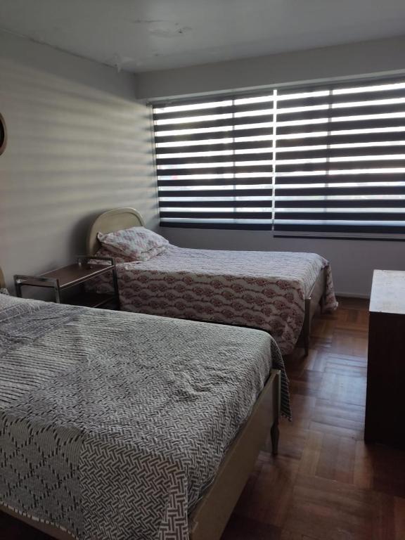 a bedroom with two beds and a window with blinds at Departamento Copacabana in Viña del Mar