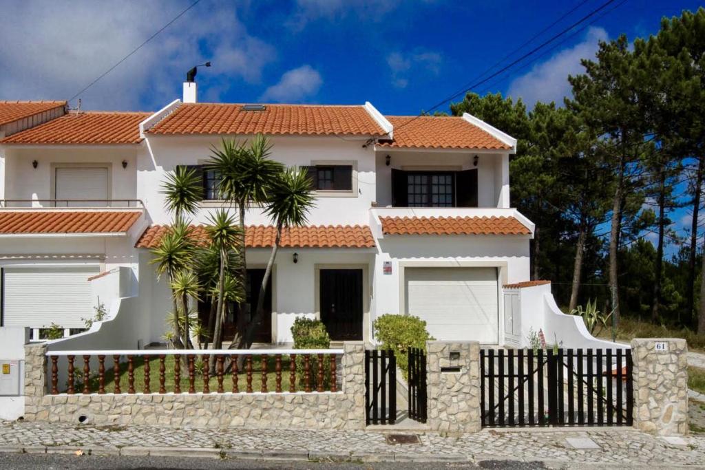 een wit huis met een hek ervoor bij West coast dream Nazare in Nazaré