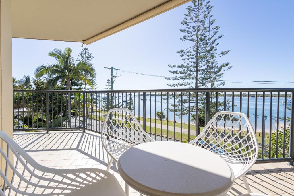 Un balcón con 2 sillas, una mesa y un árbol en Bayview Beach Holiday Apartments, en Gold Coast