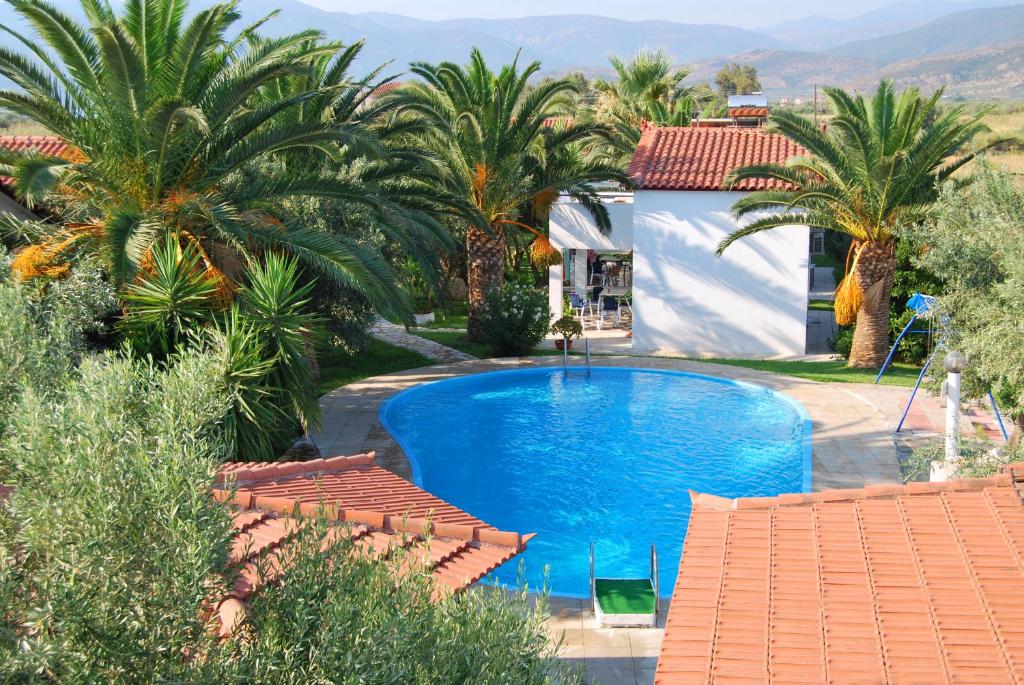 ein Pool vor einem Haus mit Palmen in der Unterkunft Houdis Houses in Paralio Astros