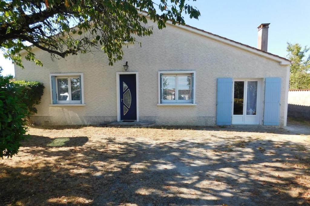 une maison avec une porte bleue et un arbre dans l'établissement Gîte MMR 6 places avec cour clôturée, à Saint-Saturnin