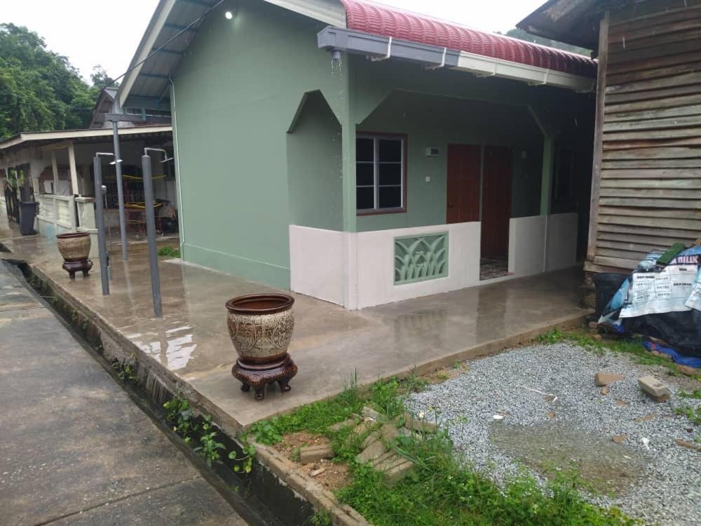 a house in the rain with a large pot in front of it at Melor Guest house in Kampong Telok Dalam