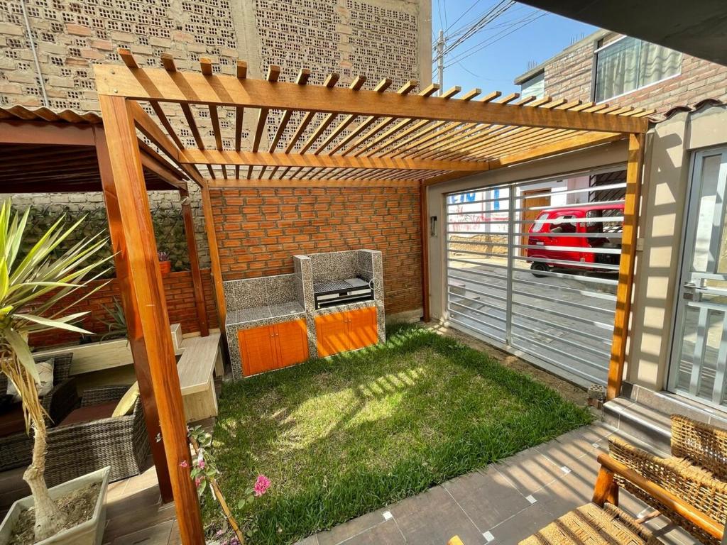 a backyard with a wooden pergola and a garage at Family Home Furnished Centro Chincha Alta in Chincha Alta