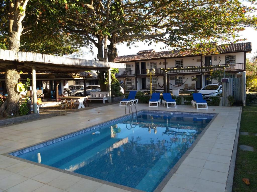 a swimming pool with blue chairs and a house at Pousada Maria Farinha in Búzios