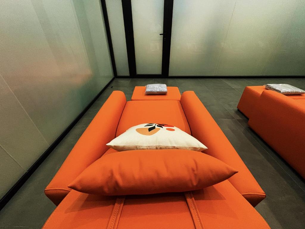 an orange couch with a pillow in a room at 사이공 트래블 라운지 Saigon Travel Lounge in Ho Chi Minh City