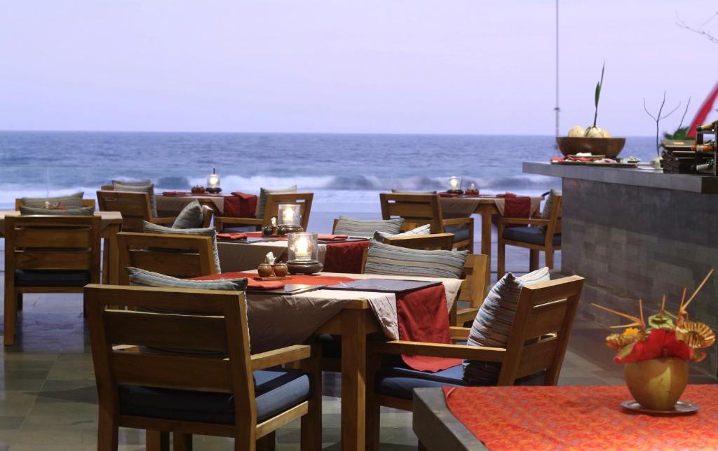 a restaurant with tables and chairs with the ocean in the background at Kelapa Retreat & Spa in Pulukan