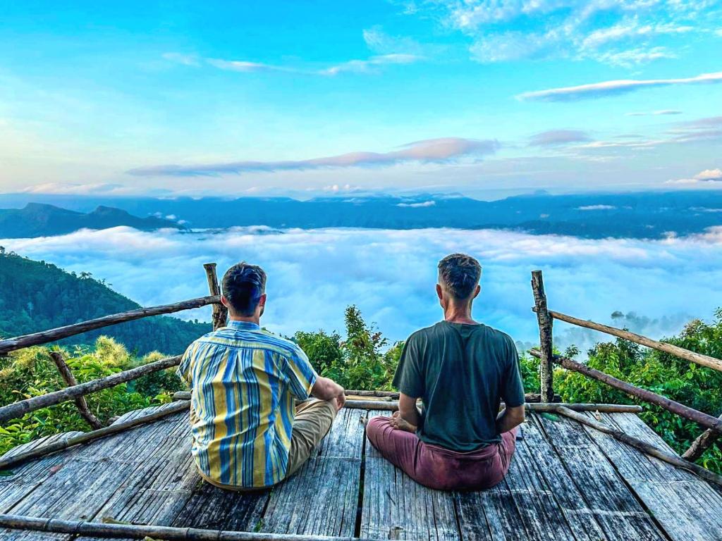 two men sitting on top of a viewing platform in the mountains at Salawin Fruit Jungle Farmstay in Ban Sob Moei