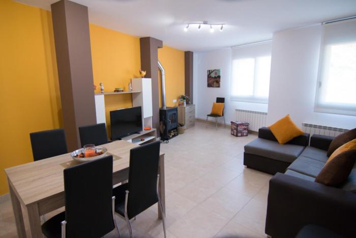 Apartament Bagà في باغا: غرفة معيشة مع طاولة وغرفة معيشة مع أريكة