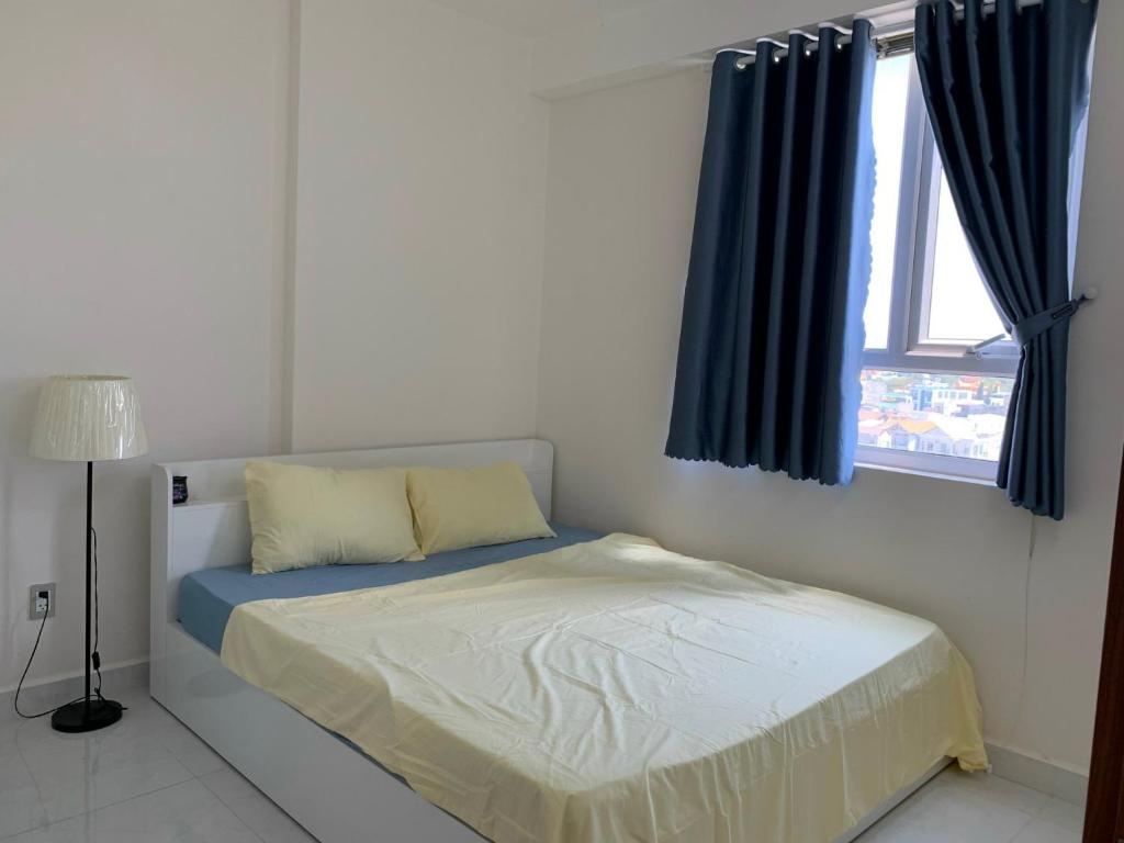 Kinh DinhにあるApartment 2BR 2WC Hacom Phan Rangのベッドルーム1室(青いカーテン、窓付)