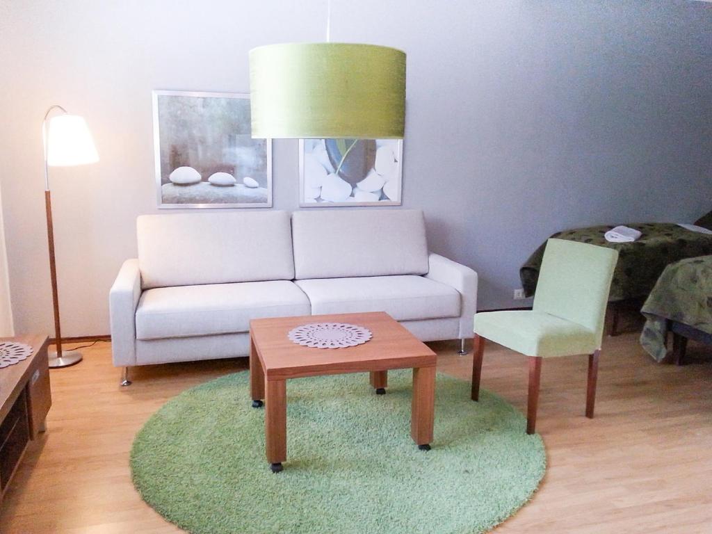 een woonkamer met een bank, een tafel en een stoel bij Apartment Kukkarokivenkatu in Mänttä