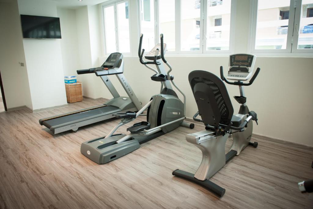 A light-filled workout room with cardio machines and a wall-mounted TV.