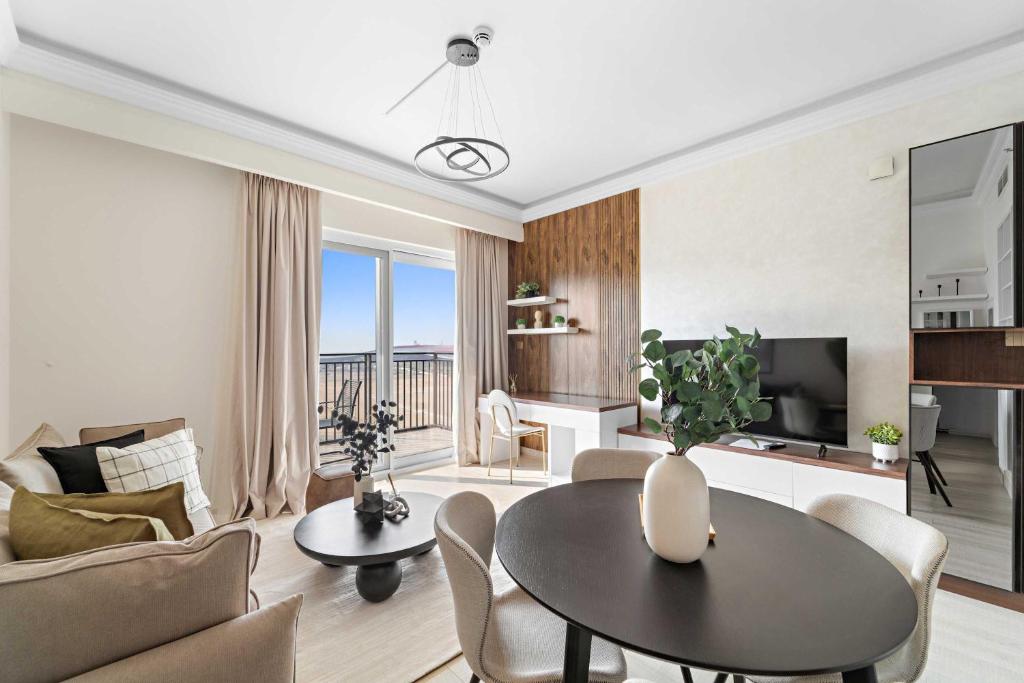 a living room with a table and a couch and a tv at Silkhaus Canalside 1BR at Water's Edge in Yas Island in Abu Dhabi