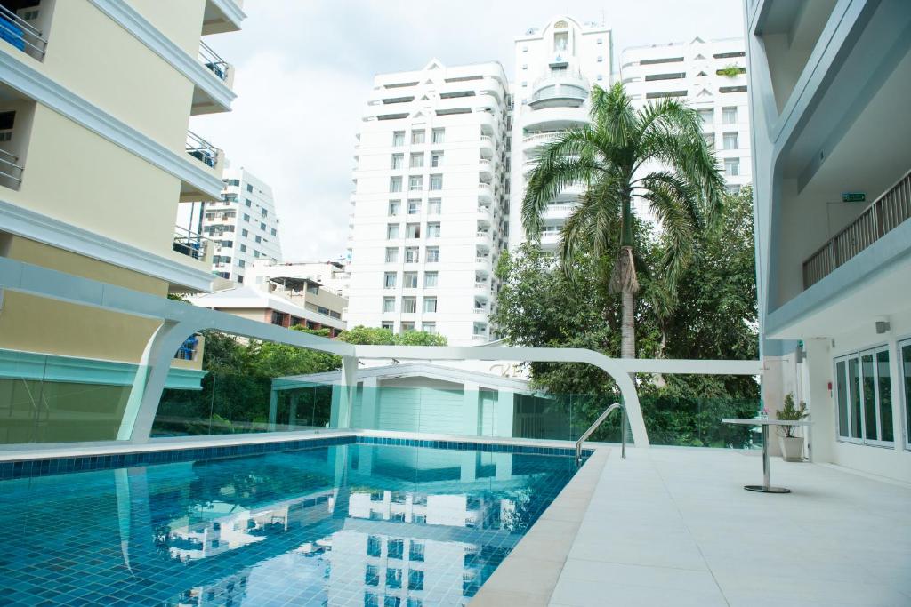 An outdoor pool courtyard framed by apartment buildings, palm trees, and a pale tiled deck.
