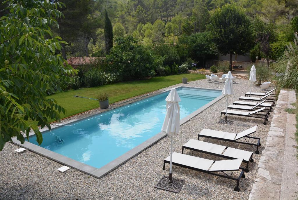 a swimming pool with lounge chairs and umbrellas at Le Mas des Aludes in La Destrousse
