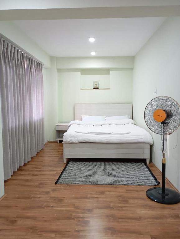 a bedroom with a bed and a floor fan at Studio Apartment Pilachhen Jasinani in Pātan