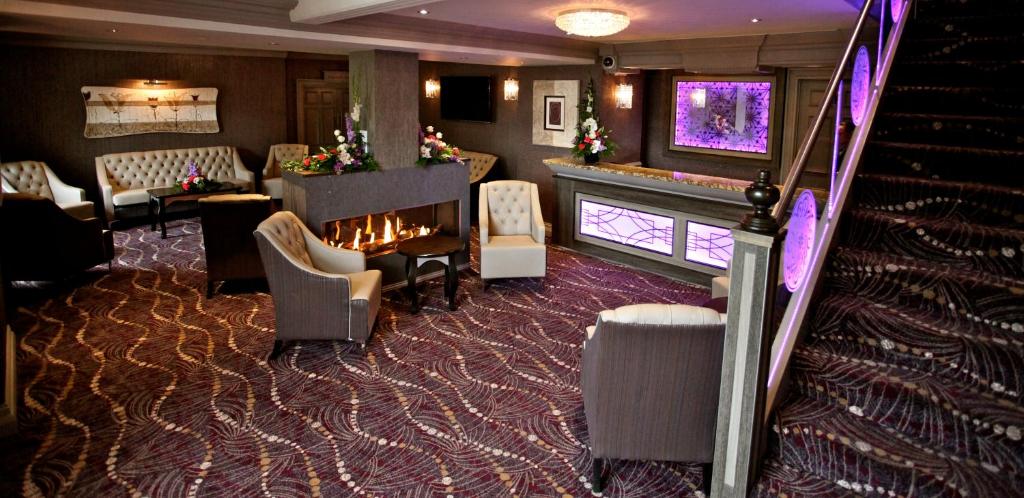 a room with a fireplace and chairs and a staircase at Greenvale Hotel in Cookstown