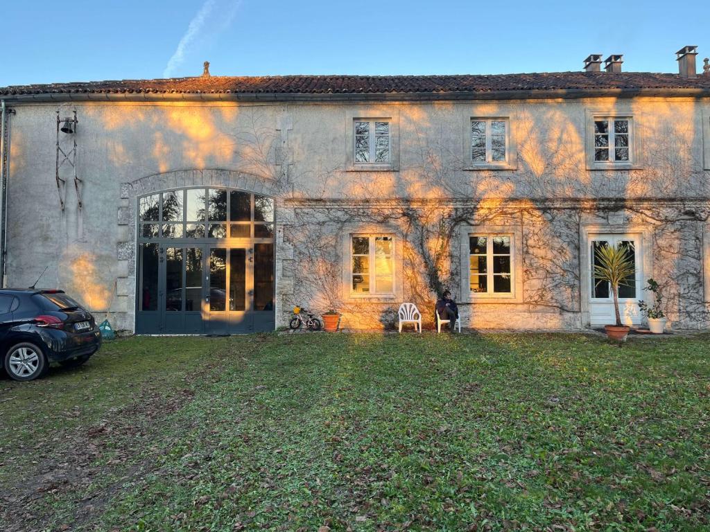 une maison en pierre avec une voiture garée devant elle dans l'établissement La Charentaise Dorée, à Juillac-le-Coq