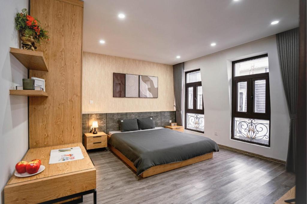 a bedroom with a bed and a desk and two windows at Merci Hoang Huy Riverside Hai Phong in Hai Phong