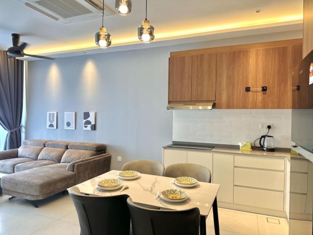 a kitchen and living room with a table and a couch at Podium apartments in Kuching