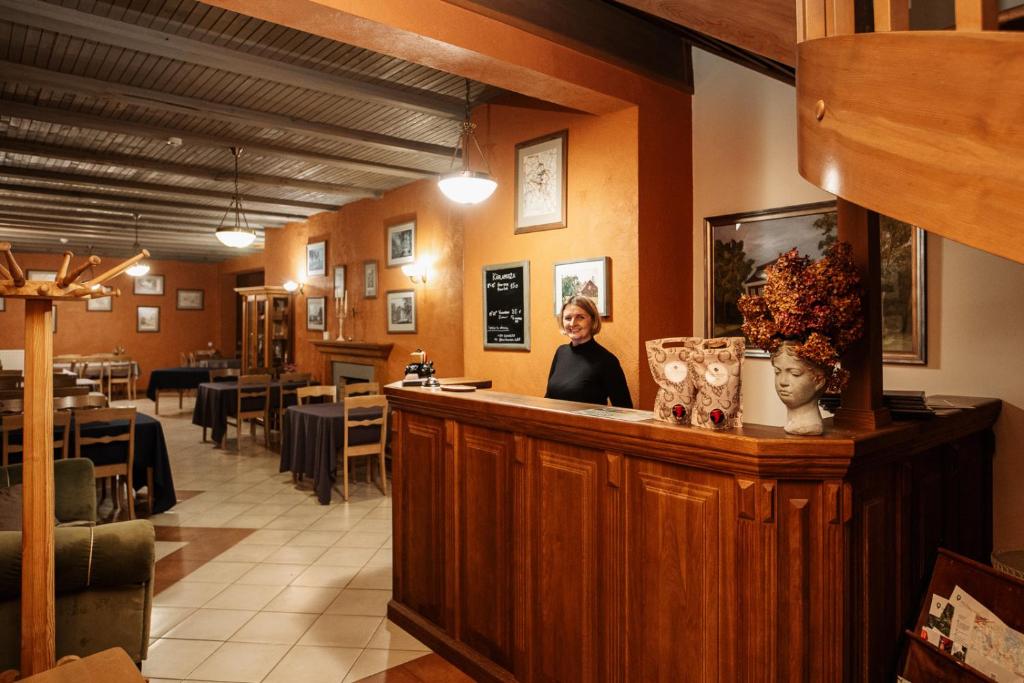a woman standing at a bar in a restaurant at Karlamuiza Country Hotel in Kārļi