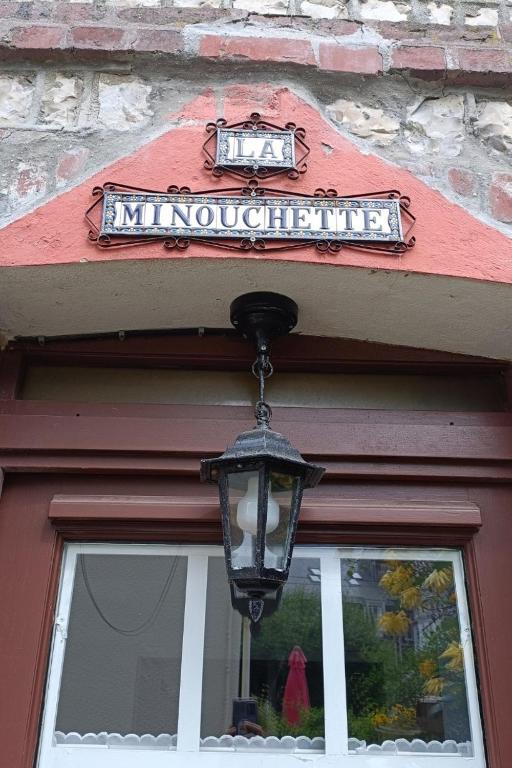 un panneau au-dessus d'une porte avec une lampe au-dessus d'une fenêtre dans l'établissement La minouchette, à Étretat