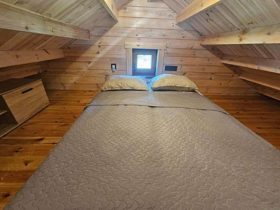 Cama grande en habitación con paredes de madera en Sodyba pas Martyna, en Triušiai