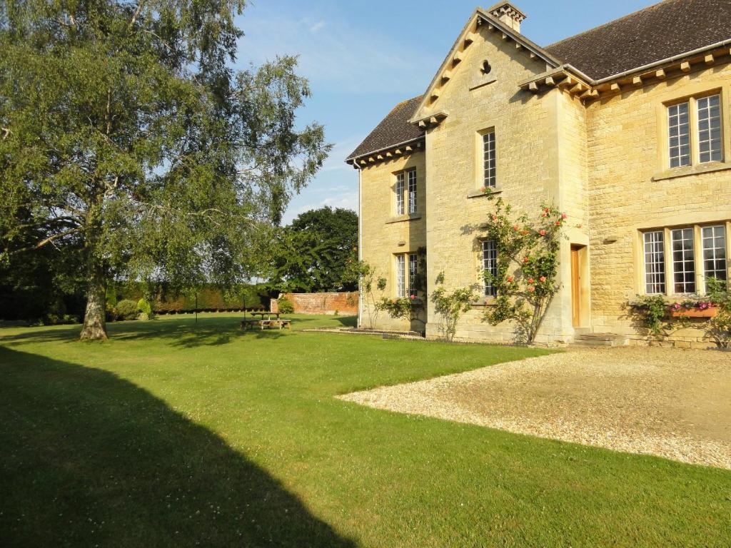 una gran casa de ladrillo con un patio de hierba en The Moretons Farmhouse, en Gloucestershire