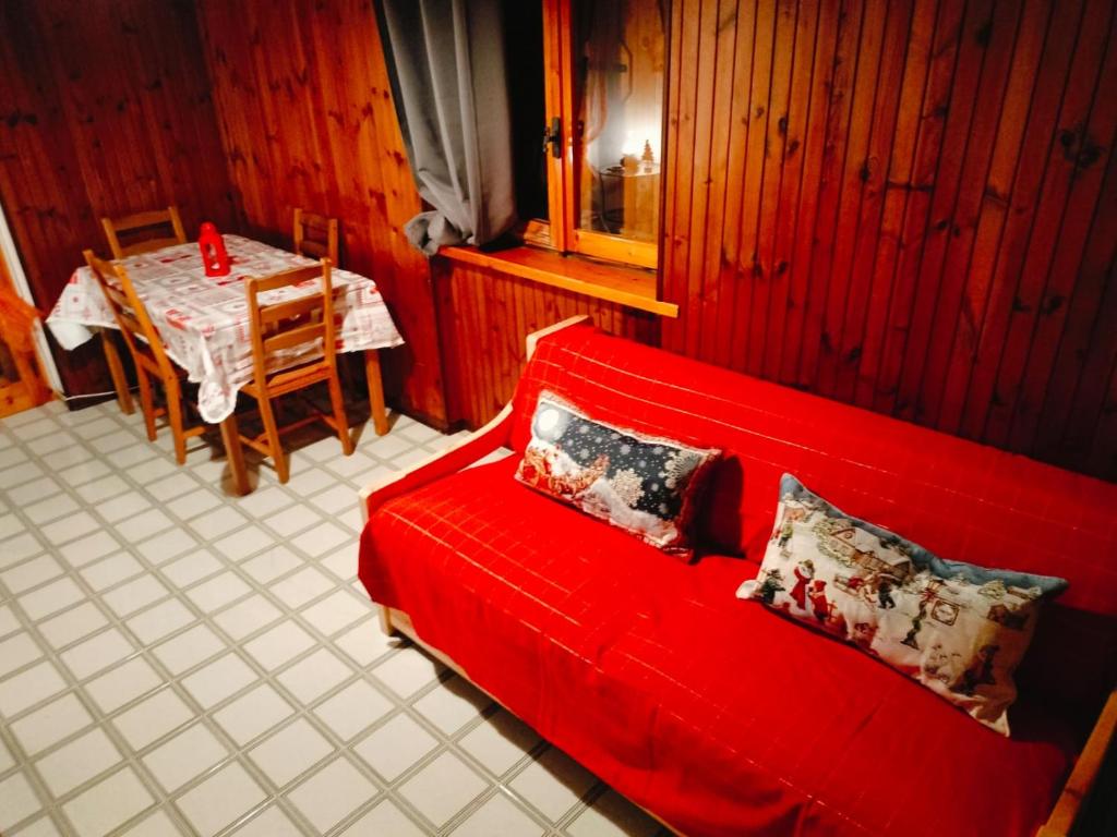 een rode bank in een woonkamer met een tafel bij Mirtilli in Prato Nevoso