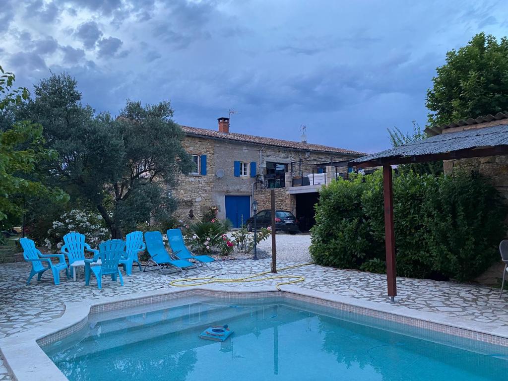 a swimming pool with blue chairs and a house at Le Mas du Bueysse in Bessas