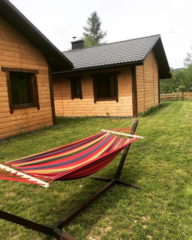 a hammock sitting in the grass in front of a house at Bieszczadzki Luz in Dwernik