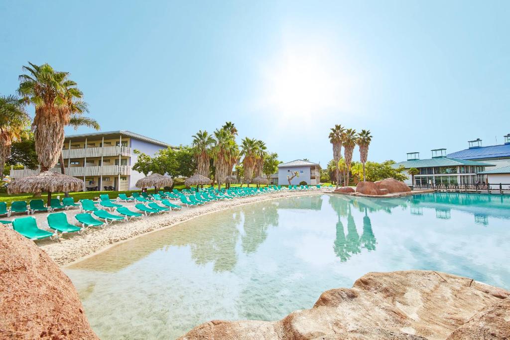 サロウにあるPortAventura Hotel Caribe - Includes PortAventura Park Ticketsの青い椅子とヤシの木がある大きなスイミングプール