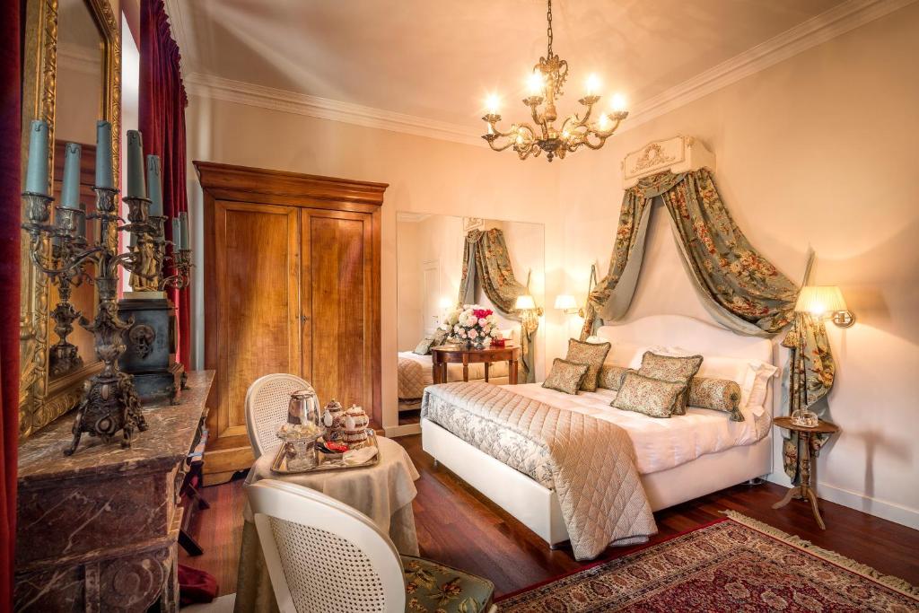 a bedroom with a bed and a chandelier at Duchessa Margherita Chateaux & Hotels in Vicoforte