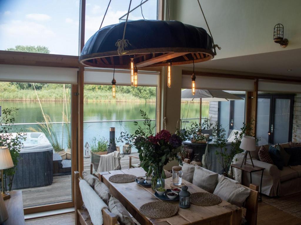 ein Esszimmer mit einem Tisch und Blick auf das Wasser in der Unterkunft Libelle Lodge in South Cerney