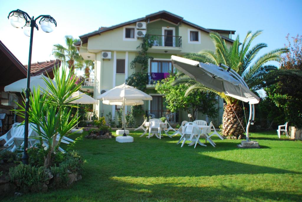 a yard with chairs and umbrellas in front of a house at Crescent Hasirci Hotel in Dalyan